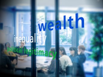 A group of people sits in a meeting room, visible through a glass wall displaying the words "wealth," "inequality," and "political legitimacy."