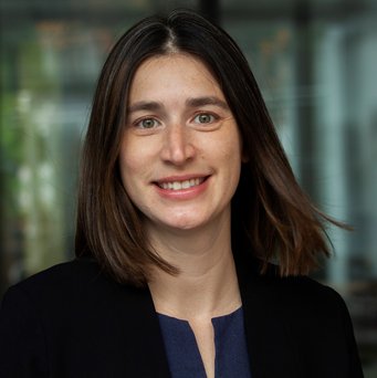 Kathleen Griesbach Junges, vermutlich weibliches Exemplar der Gattung Homo sapiens intellectualis. Es trägt mittellanges, dunkles Haar, offen zur Mitte gescheitelt, zaghaft freundlich lächelnd dem Betrachter zugewandt.