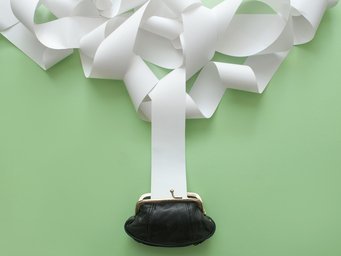 Die Inflation lässt die Preise steigen – und ein Ende ist nicht in Sicht. Bisher haben zurückhaltende Tarifabschlüsse dafür gesorgt, dass sich keine Lohn-Preis-Spirale entwickelt. Die Europäische Zentralbank sollte das in ihrer Zinspolitik berücksichtigen – so die Empfehlung von Martin Höpner vom Max-Planck-Institut für Gesellschaftsforschung. Eine schwarze Geldbörse auf einem grünen Hintergrund, aus der sich lange, weiße Papierstreifen erstrecken und den oberen Bereich des Bildes füllen.