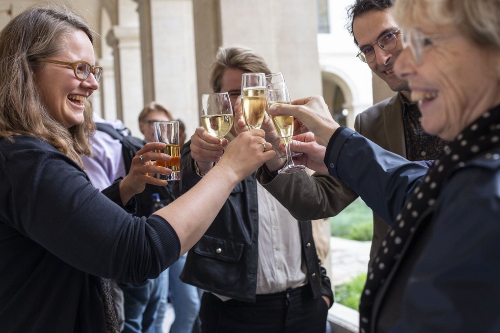 Eine Gruppe von Menschen, die mit erhobenen Gläsern feiert und in fröhlicher Runde anstößt.
