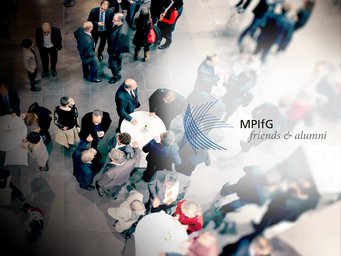 An aerial view of a professional networking event featuring numerous attendees in conversation around tables. The logo for MPIfG friends & alumni is prominently displayed, indicating the affiliation of the gathering.