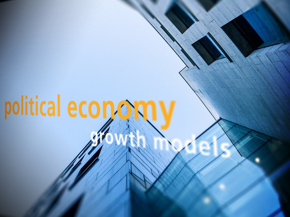 Upward view of modern buildings with reflective glass facades, featuring superimposed text "political economy" in orange and "growth models" in white, suggesting themes of economic growth and development.