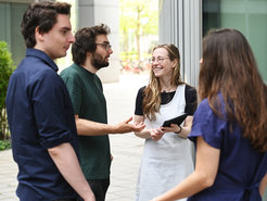 Diverse Exemplare der Gattung Homo sapiens intellectualis sowohl männlichen wie weiblichen Geschlechts sind auf dem Foto erkennbar, in freundschaftlich-kollegialer Weise einander zugewandt.