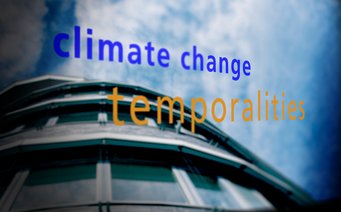 Blurred building facade with reflective glass panels, set against a partly cloudy sky, featuring text "climate change temporalities" in blue and orange.