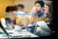 Conference setting with focus on text "MAX CPE Workshop Series: Comparative Political Economy," featuring laptops on a table and attendees in the background.