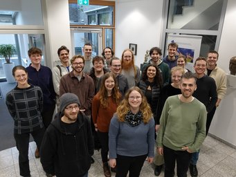 Das Foto zeigt jüngere Exemplare der Gattung Homo sapiens intellectualis, versammelt zu einem Gruppenfoto im Foyer des MPIfG anlässlich ihres Interessebesuches am Institut.