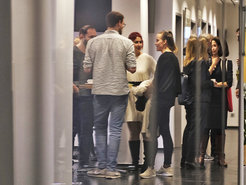 New Visiting Researchers in Summer Semester 2025. A group of people stands in a corridor, engaged in conversation, with some holding drinks and others in casual attire.