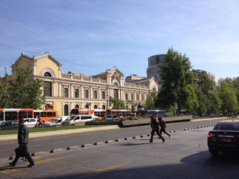 UCEN, Chile: Grand historic building featuring arched windows and detailed facade, with pedestrians crossing a busy street lined with vehicles and trees.
