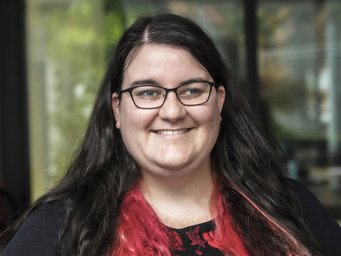 Eine Person mit langen, dunklen Haaren und roten Spitzen steht vor einem unscharfen Hintergrund, der auf eine Umgebung im Freien hinweisen könnte. Ein Foto zeigt Danielle Pullan, die im August 2025 Assistenzprofessorin in den USA wird.