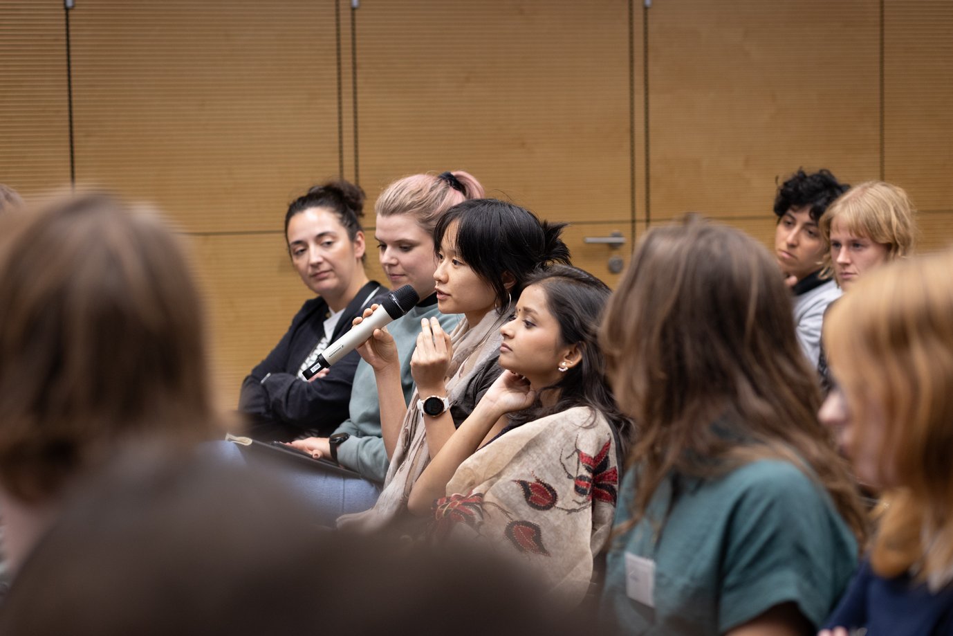 Eine Zuschauerin einer Podiumsdiskussion stellt eine Frage