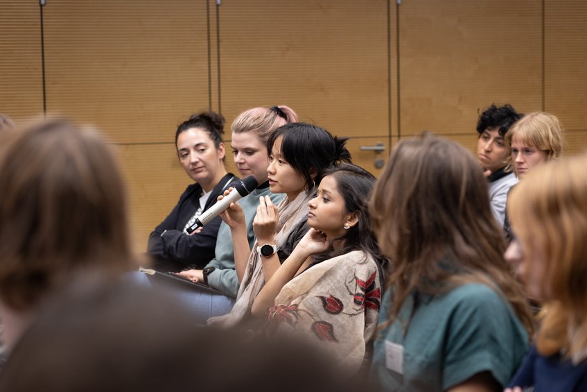 Eine Zuschauerin einer Podiumsdiskussion stellt eine Frage