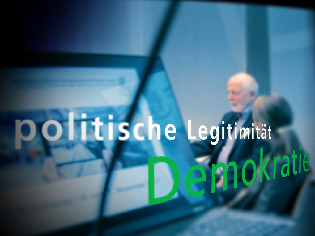 Laptop zeigt eine Webseite, während die Wörter "politische Legitimität" und "Demokratie" im Vordergrund hervorgehoben sind. Im Hintergrund Personen in einem Gespräch.