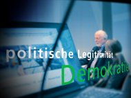 Laptop zeigt eine Webseite, während die Wörter "politische Legitimität" und "Demokratie" im Vordergrund hervorgehoben sind. Im Hintergrund Personen in einem Gespräch.
