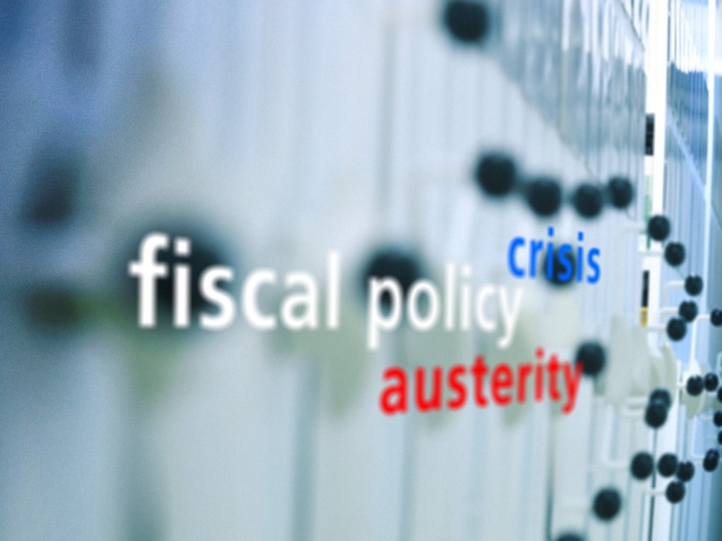 Unscharfes Bild mit den Worten „Fiskalpolitik“, „Krise“ und „Sparmaßnahmen“ im Fokus. Die Worte deuten auf Themen im Zusammenhang mit wirtschaftlichen Belastungen hin.