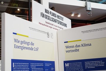 Display panels at the Max Planck Institute for the Study of Societies discuss societal challenges in the climate crisis, focusing on energy transition and climate migration.