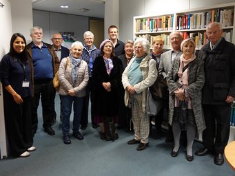 The photo shows a group of senior citizens in front of a bookshelf.