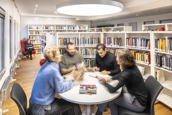 Vier Personen um einen Tisch in der Bibliothek