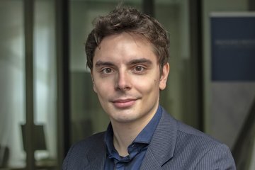 Person in a striped suit, background with glass wall and poster.