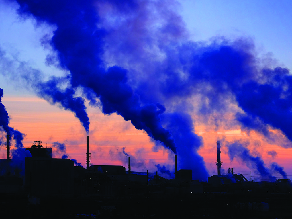 Industrieanlagen vor Sonnenuntergang, blauer Rauch steigt auf.