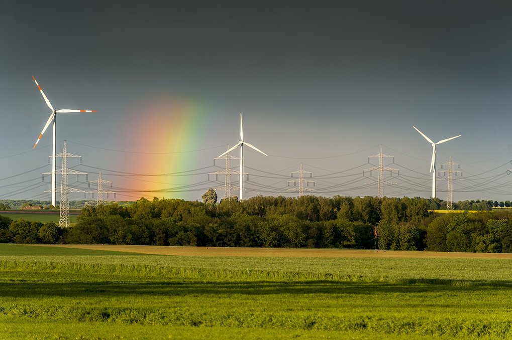 Wind turbines of a wind power plant on the horizon with a rainbow and a receding thunderstorm with a green meadow in the foreground. Credit: istock/Frank Wagner