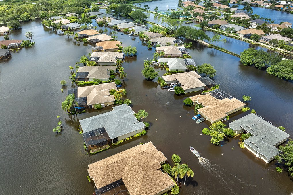 Hurricane Debby flooded street in Sarasota, Florida. Victims boating on rainfall flood waters between rural homes in residential area. istock/Bilanol