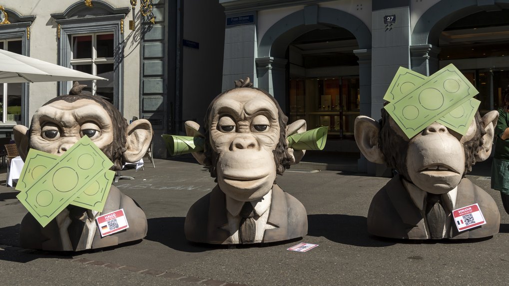 Drei Affenstatuen, eine mit Geldscheinen vor dem Mund, eine mit Geldscheinen in den Ohren, eine vor den Augen. 