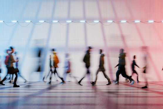 Menschen in Bewegung vor einer beleuchteten Wand mit Linienmuster.