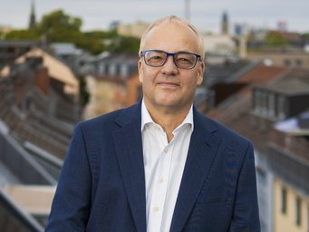 Jens Beckert, seit 2005 Direktor am Max-Planck-Institut für Gesellschaftsforschung, befasst sich mit Erwartungen im wirtschaftlichen Handeln, der Soziologie des Marktes, Erbschaften und Vermögensungleichheit und anderem. Mann im blauen Anzug vor Stadtkulisse: Jens Beckert