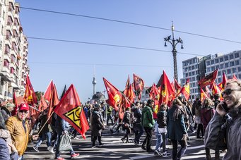 A demonstration with many red flags and numerous participants in a city.