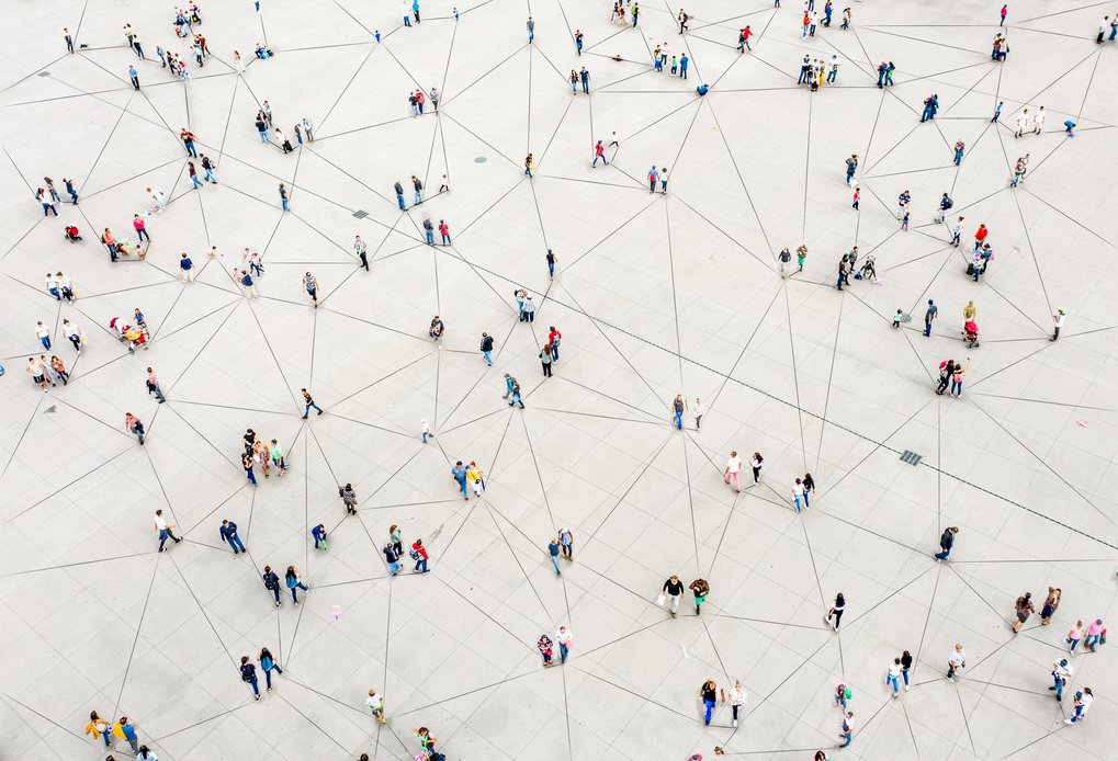 Auf einem weiten Platz sind viele Menschen verteilt, die durch ein System von Linien miteinander verbunden sind und ein Netzwerk bilden.