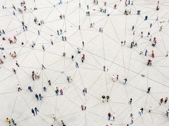 Auf einem weiten Platz sind viele Menschen verteilt, die durch ein System von Linien miteinander verbunden sind und ein Netzwerk bilden.