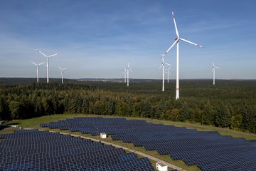 Eine ausgedehnte Waldlandschaft mit zahlreichen Windrädern ist zu erkennen.