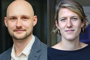 Nahaufnahmen von zwei Personen vor neutralem Hintergrund, links ein Mann mit Glatze und Bart in weißem Hemd und grauem Sakko, rechts eine Frau mit kurzen blonden Haaren und goldenen Creolen.