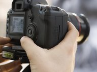 Close-up of a hand adjusting a professional DSLR camera mounted on a tripod.