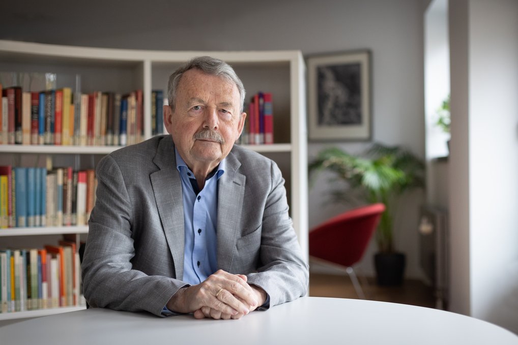 Wolfgang Streeck sitzend an einem Tisch vor einem Bücherregal.