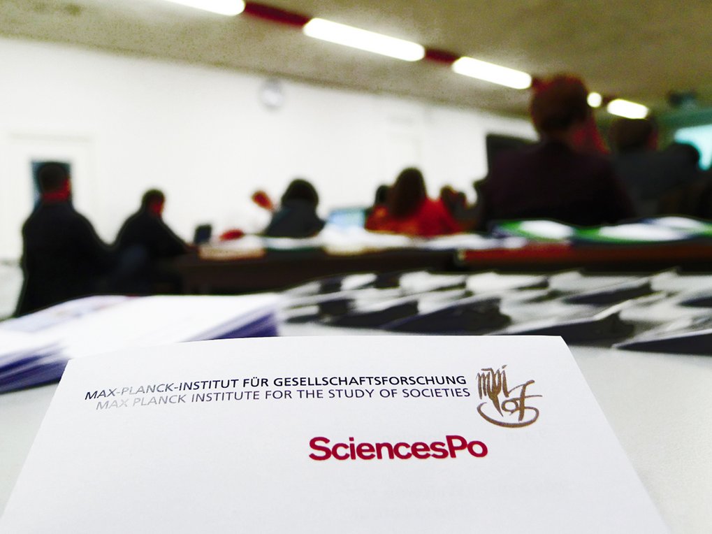 Eine Gruppe von Personen in Business-Anzügen und formeller Kleidung sitzt in einem Konferenzsaal und klatscht aufmerksam, was ihr Interesse an der Veranstaltung zeigt.