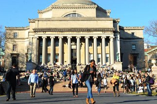 Eine Gruppe von Menschen versammelt sich auf den breiten Stufen der Columbia University Library, während einige sich entspannen und andere vorbeigehen.