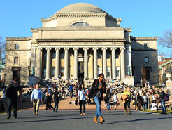 A group of people gather on the wide steps of Columbia University Library, while some relax and others walk by.