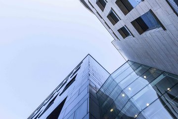 Ein von unten schräg nach oben in den Himmel weisend aufgenommenes Foto zeigt die Eckfassaden eines Gebäudes, vermutlich das des MPIfG.