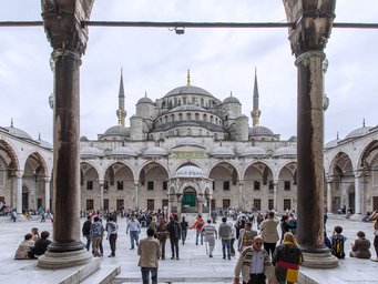 Zahlreiche Touristen und Einheimische schlendern durch den Innenhof der Blauen Moschee in Istanbul, um die beeindruckende Architektur zu bewundern.