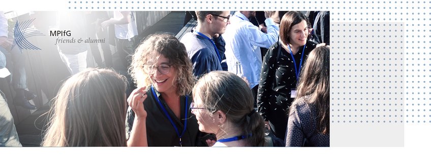 Society of Friends and Former Associates of the Max Planck Institute for the Study of Societies Group of individuals at an MPIfG event, wearing lanyards, engaging in conversation.