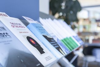 A selection of books on a library shelf, including titles on future predictions, displayed prominently in a well-lit area.