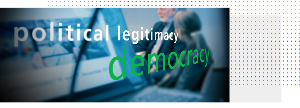 Blurred text on a glass wall with the words “political legitimacy democracy” in a conference room.