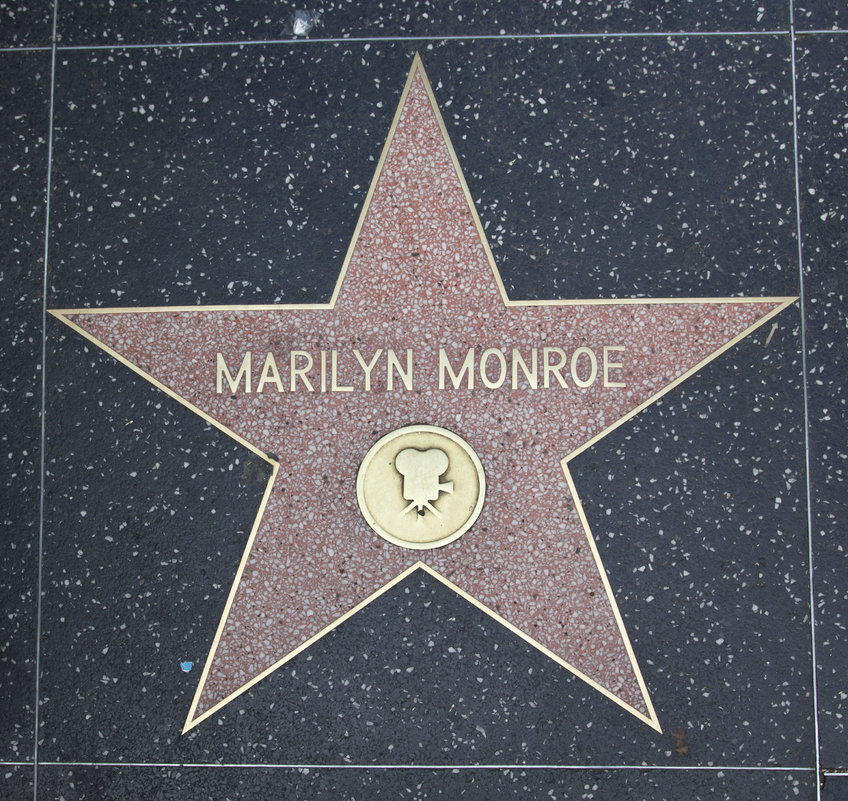 Ein rosa Terrazzo-Stern auf dem Hollywood Walk of Fame ehrt Marilyn Monroe mit ihrem Namen in goldenen Lettern und einem Filmkamerasymbol. A pink terrazzo star on the Hollywood Walk of Fame honors Marilyn Monroe, with her name in gold lettering and a film camera symbol.