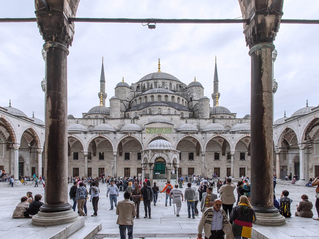 Numerous tourists and locals stroll through the courtyard of the Blue Mosque in Istanbul to admire its impressive architecture.