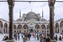 Numerous tourists and locals stroll through the courtyard of the Blue Mosque in Istanbul to admire its impressive architecture.