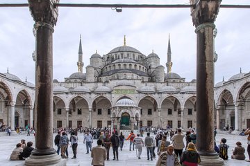 Numerous tourists and locals stroll through the courtyard of the Blue Mosque in Istanbul to admire its impressive architecture.