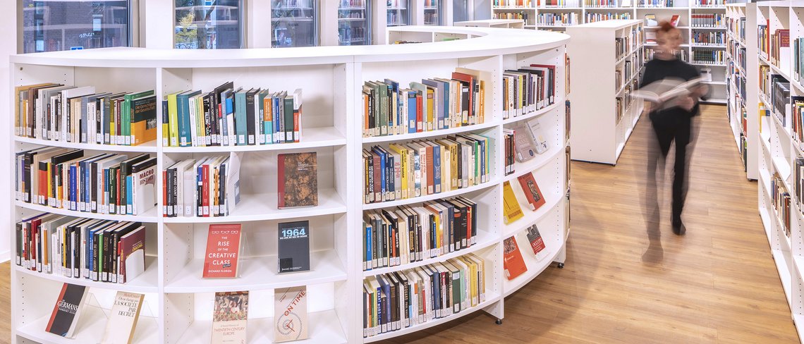 Person geht durch das Institutsbibliothek