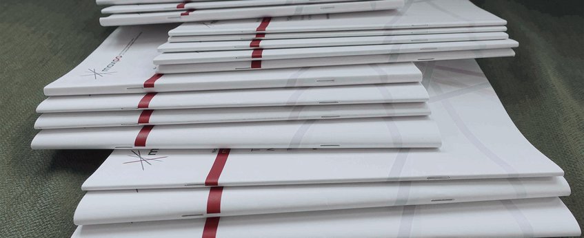 A stack of brochures or booklets with a white cover and red accents.