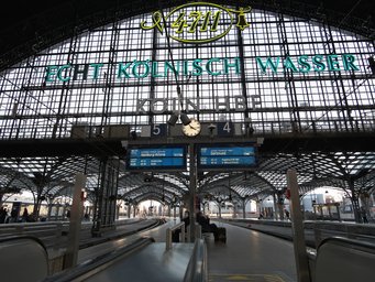 Cologne main train station View of Cologne Central Station with empty tracks, a central clock, and a prominent Echt Kölnisch Wasser advertising sign.